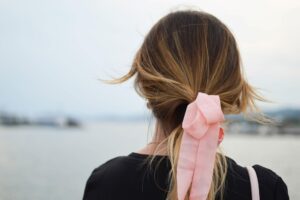 Fotografía de enfoque de mujer con lazo de pelo coquette rosa mirando hacia el cuerpo de agua